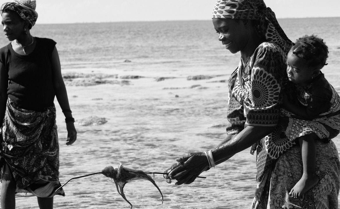 A local woman cooks octopus in the traditional way on the beach on Vamizi Island.